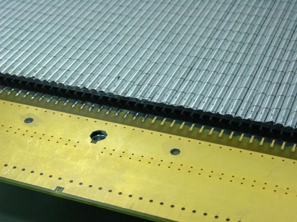 Fragment detektora słomkowego. Słomki, przez które przelatują cząstki elementarne, są widoczne w górnej części zdjęcia. Źródło: IPJ