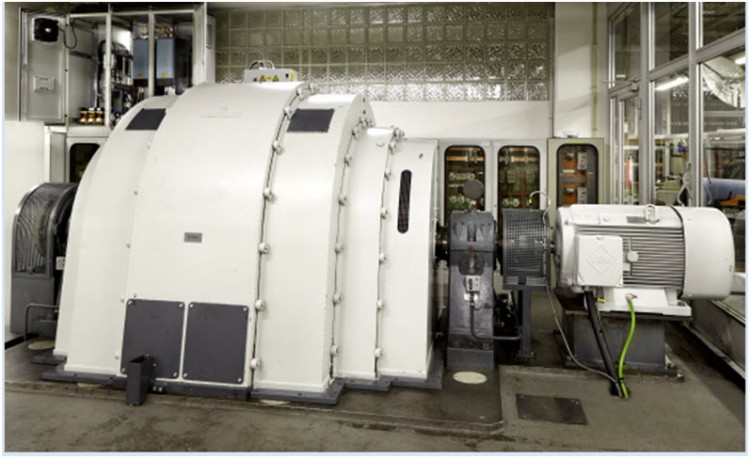 Po prawej generator udarowy w laboratorium badawczym I²PS GmbH; po lewej, za otwartą szafą rozdzielczą z rozwiązaniem napędowym Eaton, widoczny nowy silnik asynchroniczny.