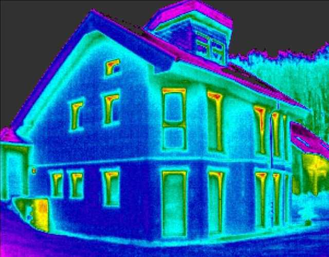 Obraz domu pasywnego z kamery termowizyjnej. Ciemnoniebieski kolor oznacza niskie straty ciepła w porównaniu do budynku znajdującego się obok (zielony kolor ścian).